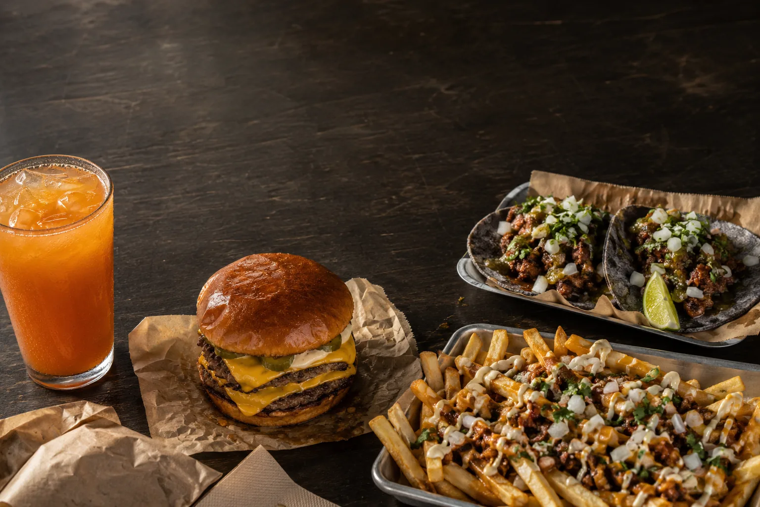 A full Pacheco spread: burger, tacos, a loaded side and an agua fresca.